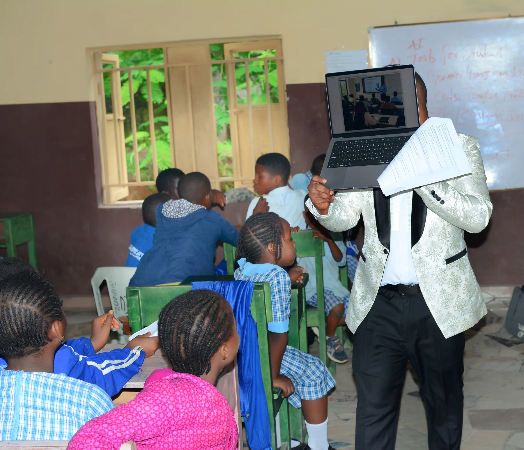 A classroom seen from the back, a laptop held up at the front